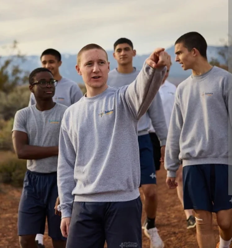 A group of young men in athletic wear standing together outdoors, one pointing toward the horizon.