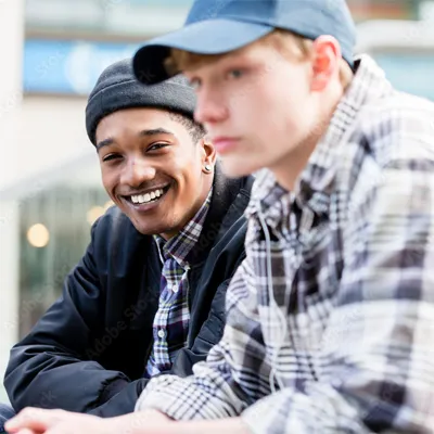 Two young men sitting side by side and smiling in a bright community space.